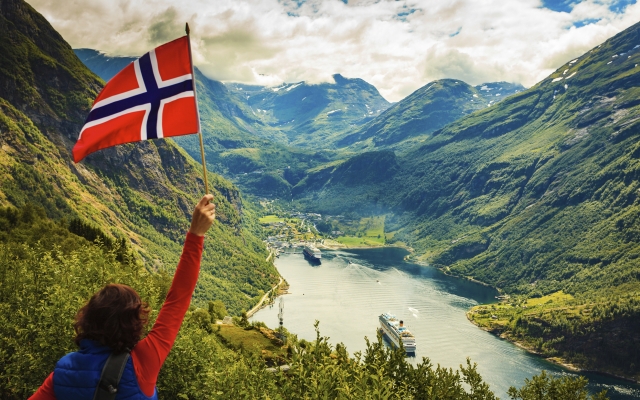 Tourist over Geirangerfjord with norwegian flag